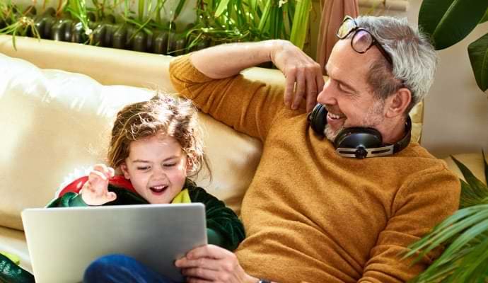 Mężczyzna w słuchawkach pokazujący coś dziewczynce na laptopie